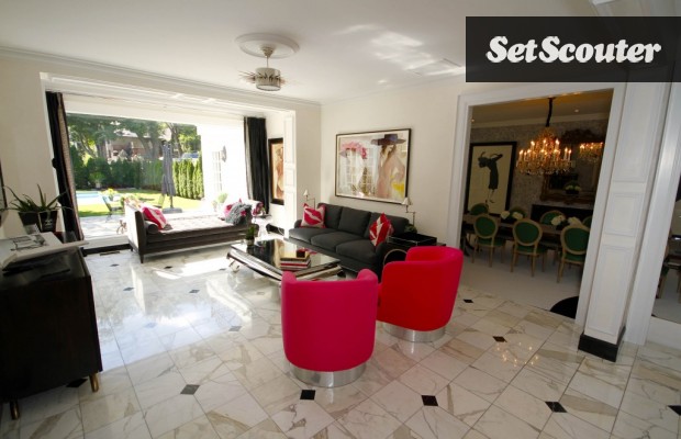 The living room in Karen's home features hot pink accents in an otherwise classic black and white room. An entire wall even opens onto a beautifully manicured backyard with large pool.