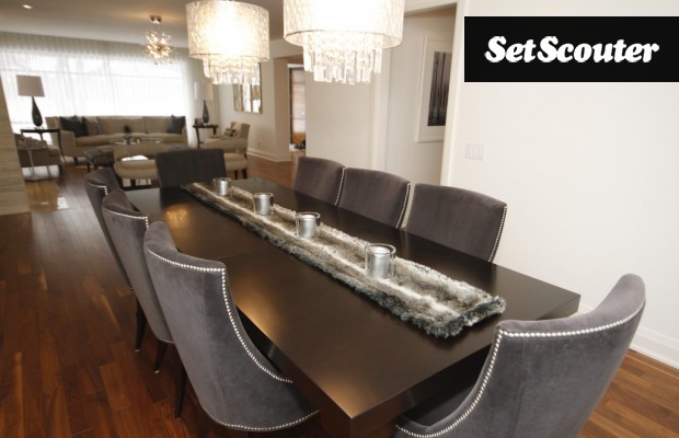 The elegant dining room in this home provides seating for eight with gorgeous light fixtures above. This open concept area is connected to the living room which boasts minimal, transitional furnishings.