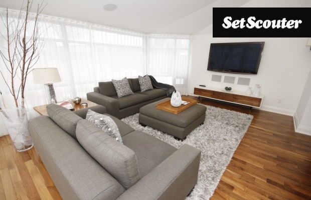 This large family room is full of crisp, neutral tones and grey variances throughout. The shag carpet adds warmth to the room while the large windows let in lots of natural light for filming.