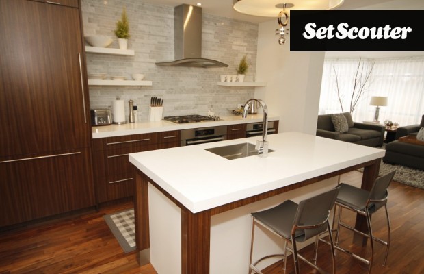 This contemporary kitchen features dark wood and white accents throughout. Chrome is used effectively in the space to give the room a clean and modern feel. This room opens up to a vaulted family room which is surrounded by walls of windows.