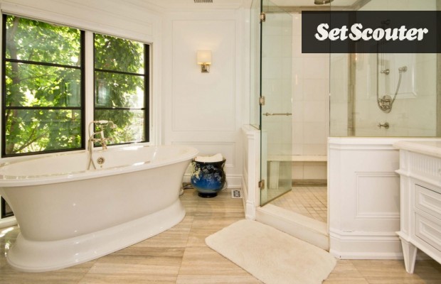 This master bathroom is spa-like with a neutral, earthy colour palette. It is complete with both a walk-in shower and soaker tub. Wainscotting and crown moulding are decor details that bring this look together.