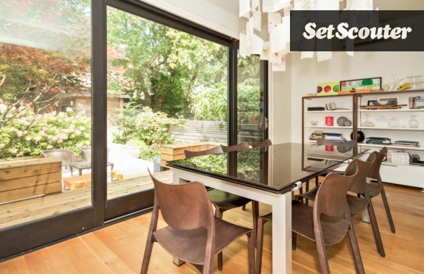 This family dining table is placed perfectly in front of a windowed wall to allow for ample natural light and a green view. The furniture in this space can easily be moved to accommodate any scene.