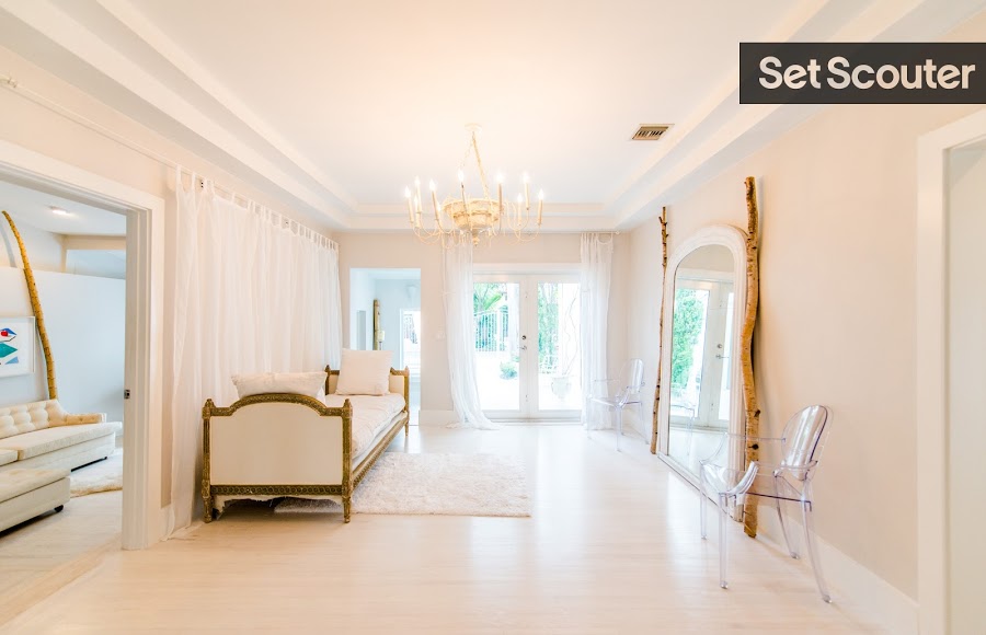 Pascal’s additional sitting room has a modern, minimalist style that offers tons of versatility for shoots. The rustic wood and gold details offset the all-white design, adding balance to Pascal’s stunning space. The mirror, chandelier and lavish ottoman allow this sitting room to double as a chic foyer for shoots!