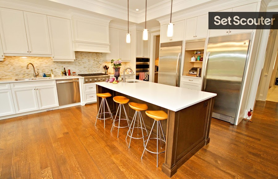 This massive kitchen is bright and upbeat with enough room to fit a small table for four in addition to this island seating. Having this gorgeous, rustic kitchen island with a sleek white counter top and modern bar stools make for the perfect spot for a trendy cooking show. Large glass doors that open up into a garden gives the space natural light and a beautiful view for any kitchen scene.