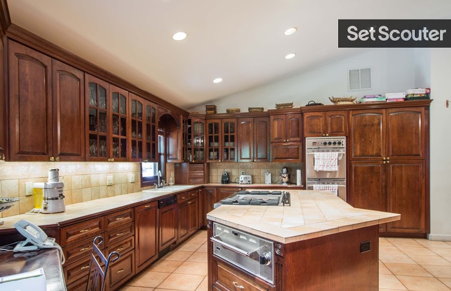 Gloria’s deep wood cabinets give the kitchen a traditional and warm look. Double ovens, a large island and a large workspace make this kitchen ideal for cooking videos requiring a lived-in, family look.