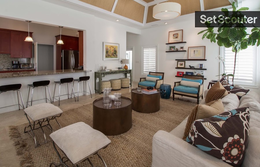 This open concept living room exudes comfort and relaxation. Wood accents and a wicker rug add an outdoorsy touch, while plants and floral pillows add fun and flair. An open concept with tons of seating makes this the perfect space to gather family and friends.