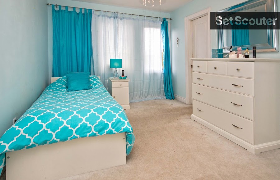 Upstairs, a kid's bedroom is decorated to match the atmosphere of sophistication. The addition of bright blue curtains and a matching bedspread gives the room youth and personality while remaining gender-neutral.