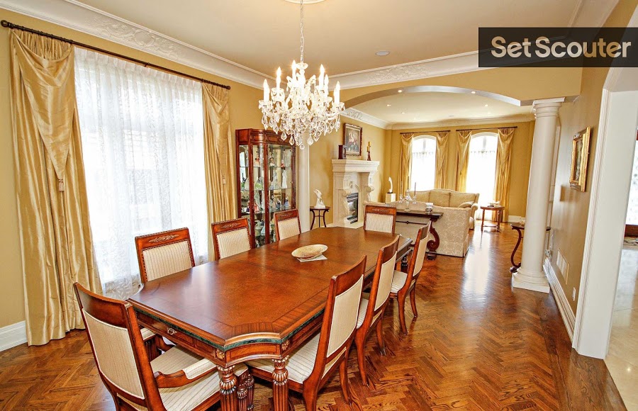 Esti makes use of her open space by creating two unique and distinctly styled rooms. An upscale dining room with a crystal chandelier and silk curtains leads into a cozy seating area with a fireplace and soft cream sofas. Little details like the herringbone wood floors, detailed crown moulding and interior pillars a to the elegance of Esti's gorgeous home.
