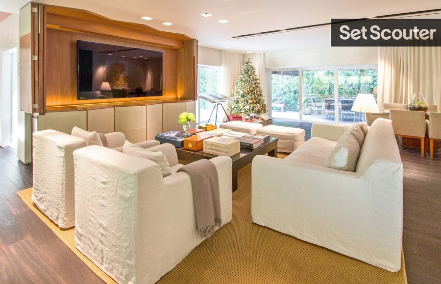 A mustard carpet is bright and playful in this comfy, living room area. Large floor-to-ceiling windows provide hints of natural light warming up the room, while a luxurious television display case towers over the cozy setup.