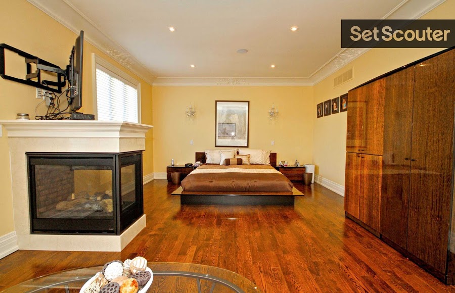 A master bedroom with earthy tones and crisp edges and corners looks sleek and modern. The wardrobe is both functional and fashionable with a new age look and traditional wood finish. A unique, encased fireplace stars as the main attraction.