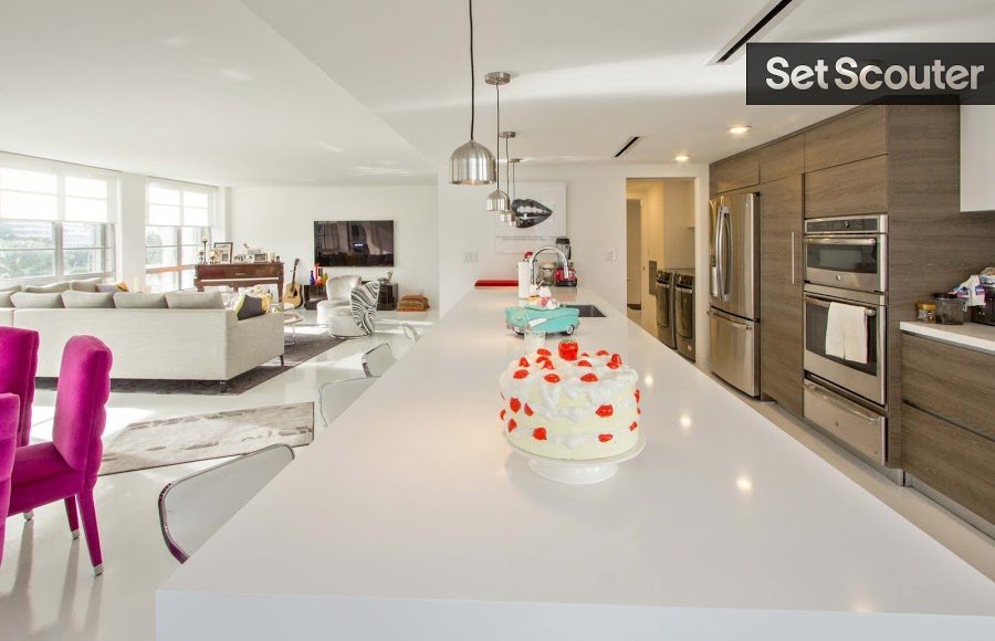 A chic white peninsula counter makes a trendy addition to this upgraded kitchen. With gourmet appliances and sleek low hanging lights, this kitchen would be the perfect backdrop for a modern cooking show or appliance commercial.