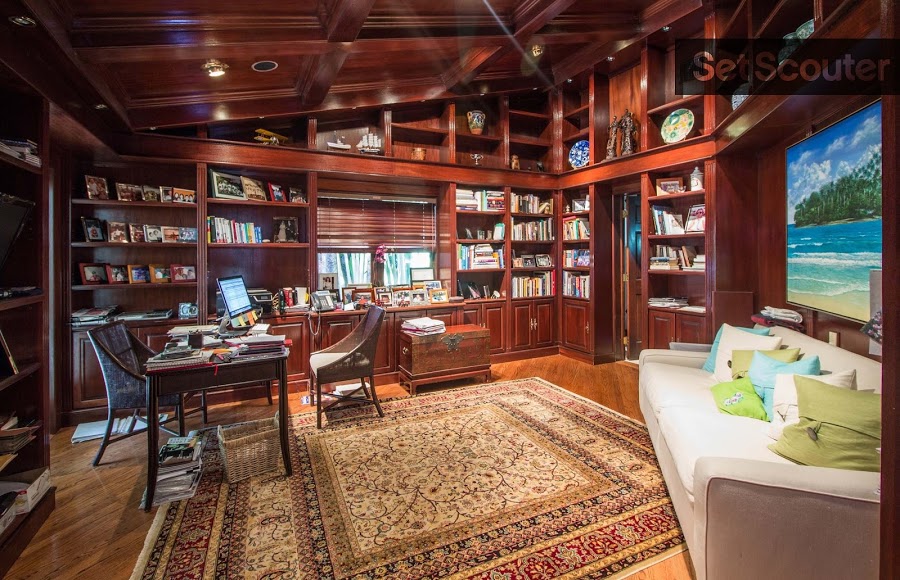 A rich, cherry wood study with an extensive library stands out from the other rooms in the house. A slanted ceiling adds an interesting shape and depth to the room. The addition of a bright couch and an ocean-view photo are a happy reminder of the Florida sun outside.
