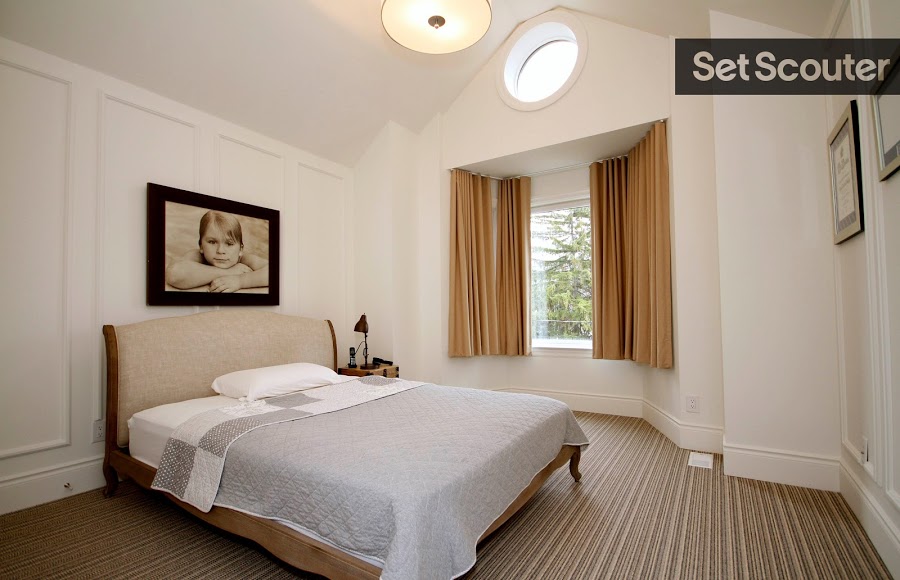 The main bedroom’s high ceilings and window nook elevate the minimalism and neutral tones tying the room together. White walls with structured detailing brighten the space and minimal décor encourages a serene and tranquil look.