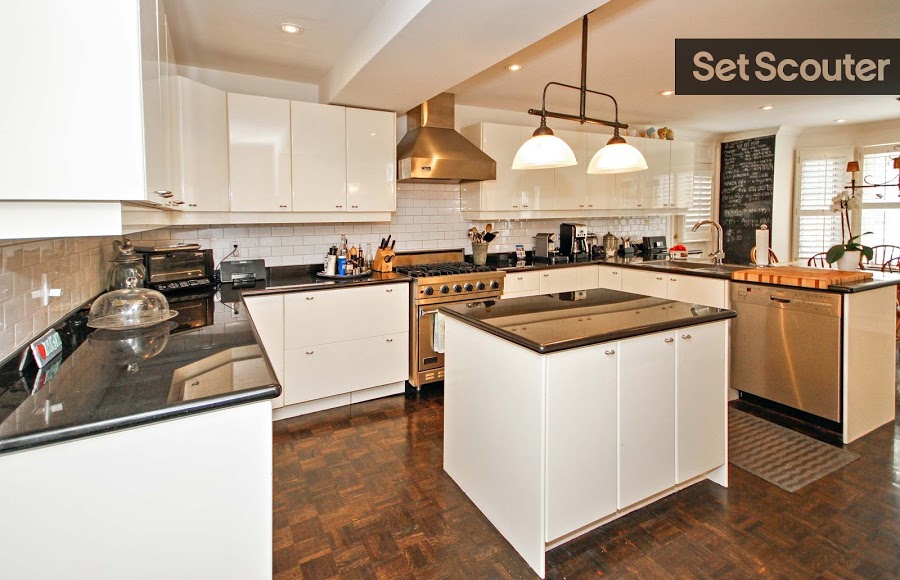 Teri's eat-in-kitchen with stainless steel accents is both stylish and cheerful. Natural light combined with the white cabinets, walls and backsplash keep this open space bright, fresh and expansive. A quaint kitchen island with a chic, vintage style over-hanging light fixture and parquet flooring add a sleek, modest touch.