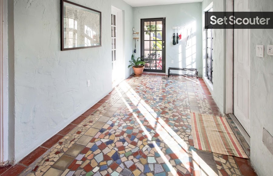 A spacious walk-through entrance features a one-of-a-kind, mosaic floor. Bright walls and natural light make this space warm and inviting while dark accents in from door frame and window paneling contrast and add a pop of modern style.