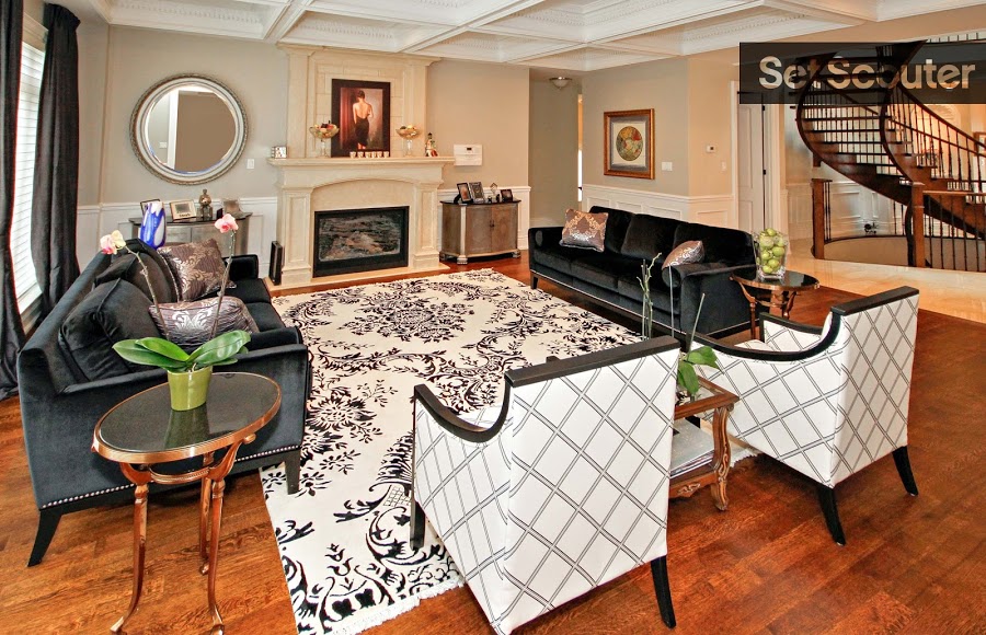 Michael’s open concept living room is modern and chic. The detailed black and white carpet pairs well with the coffered ceiling and gives this traditional space contemporary flair. Centred around a cream-coloured fireplace, rich hard-wood flooring and natural light keep the room open cozy and inviting.