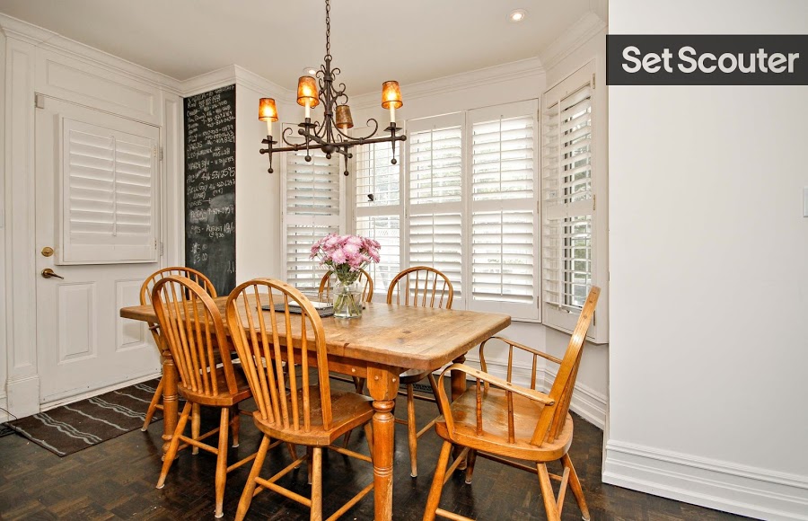 A playful dining area is set up by a bright bay window in Teri’s white kitchen. A traditional wooden dinner table, vintage light fixture and chalk board wall has a cozy charm with tons of personality.