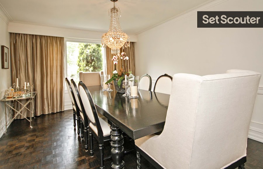 Teri's luxurious dining room is highlighted by it's traditional dark-wood table and sophisticated, modern sofa chairs. A gold side table and crystal chandelier add old-timey style to this to this modern take on a traditional space.