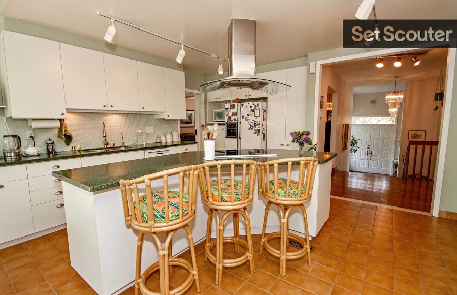 Asiye's kitchen is open and traditional while colourful bar stools brighten up space with their unique character. A center island is complete with a modern, electric stovetop and ventilation while other appliances such as the refrigerator filled with photos and magnets keep this space unique and humble.