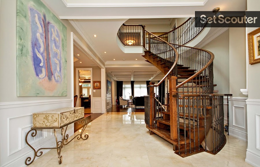 A stunning entry way accentuates a grand, spiral staircase. This jaw-dropping hallway features marble floors, crown moulding and modern artwork, while an exquisite side-table adds a historic and detailed touch.