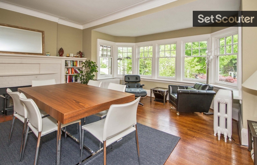 Denise's formal dining room is a sharp and sophisticated space. With a bit of retro flair, this space is filled with incredible statement pieces from the leather lounger and thick wood dining table, to the vintage-style fireplace and credenza. Massive bay windows keep this room bright and a gold-framed mirror atop the fireplace is a great illusion by Denise in keeping this smaller space big and bold.