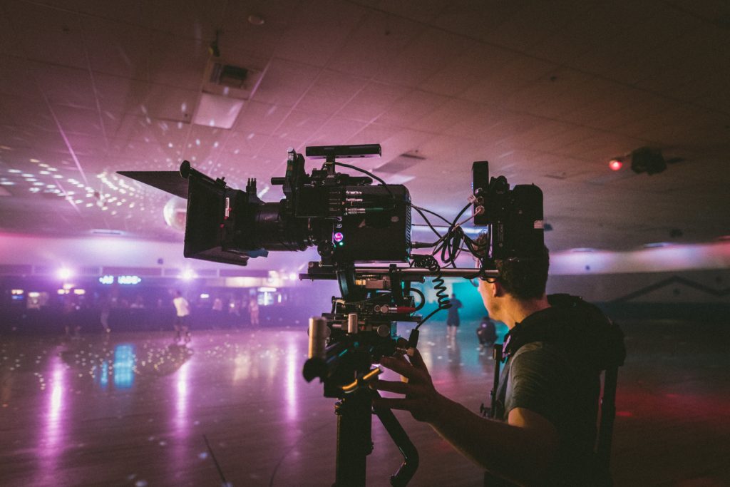 Your mental health on a film set can take a turn on a bad shoot day.  Remember sh*t happens, and it don't make you any less of a professional! Pictured: a camera man stands in a neon lit roller rink.